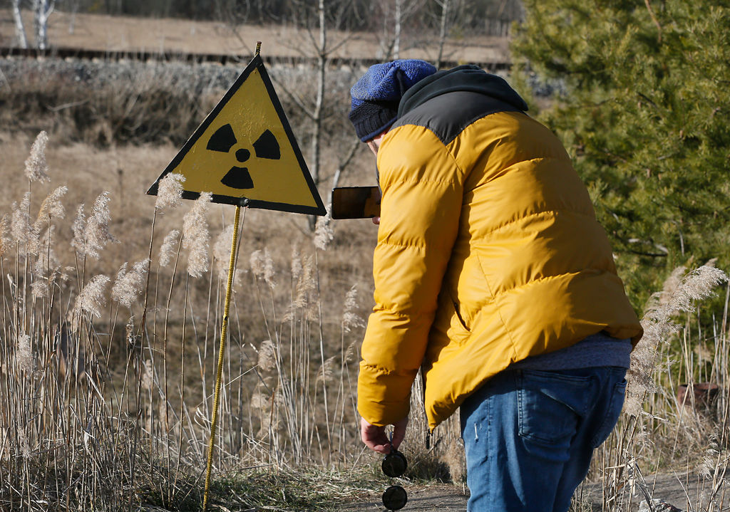 A tourist takes a photo of a radiation sign at the deserted town of Pripyat